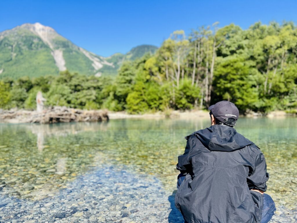 A person stands at the Azusa river in Kamikochi.