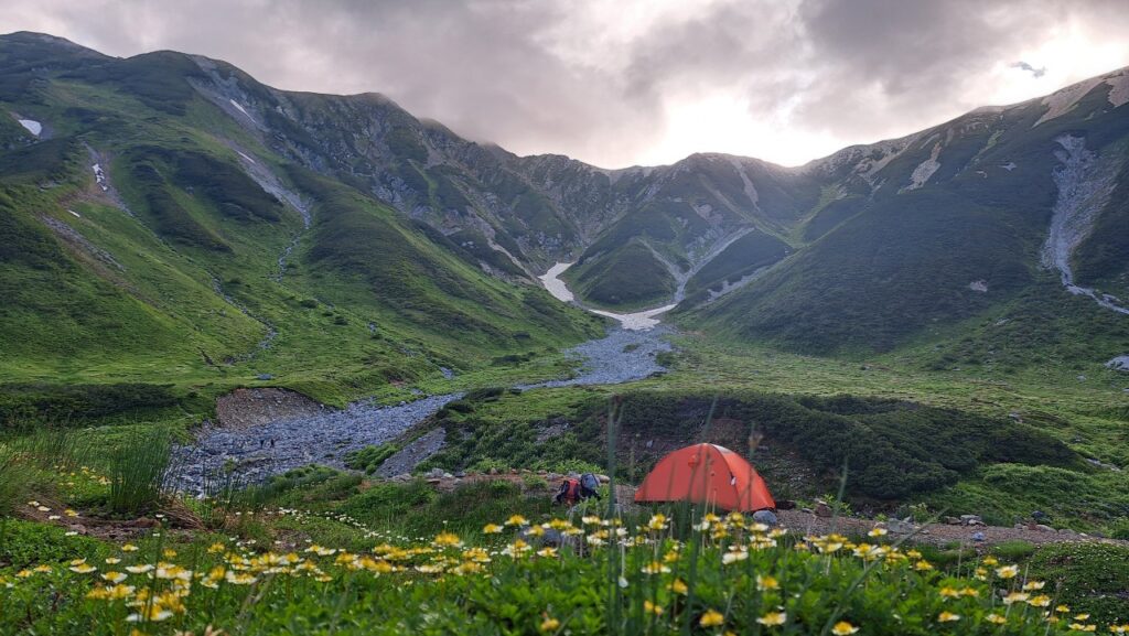 A tent set up against the backdrop of the Tateyama mountain chain in July.