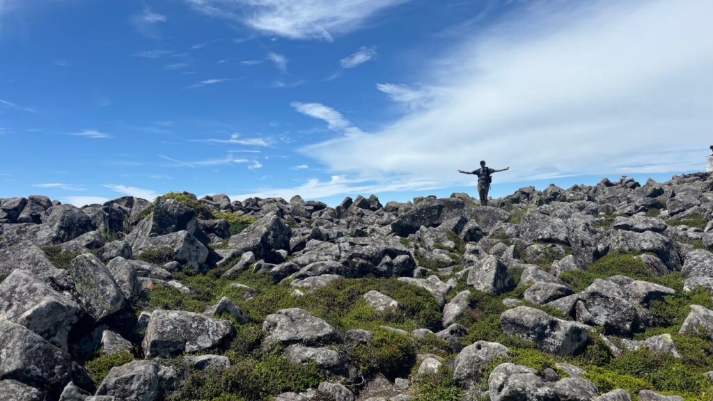 A hiker stands at the wide summit of Tateshina Mountain in Nagano, Japan.